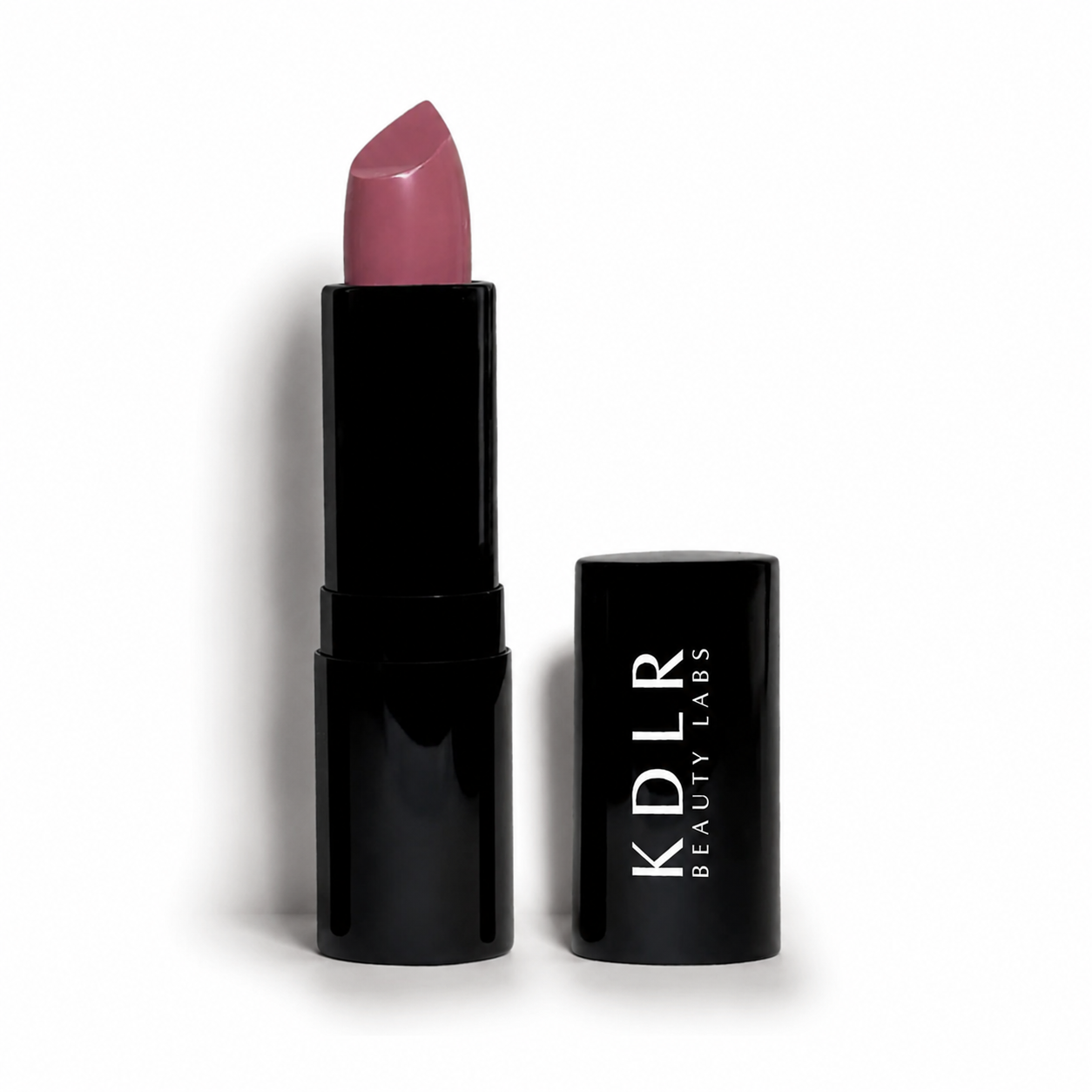 KDLR Beauty Labs Noir Patent Cream Lipstick in Magical Mauve, a creamy mauve nude satin lipstick in glossy black packaging on a white studio background.
