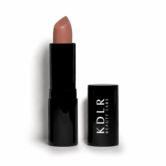 KDLR Beauty Labs Noir Patent Cream Lipstick in Naughty Nude, a creamy warm nude lipstick with a satin finish in glossy black packaging on a white studio background.