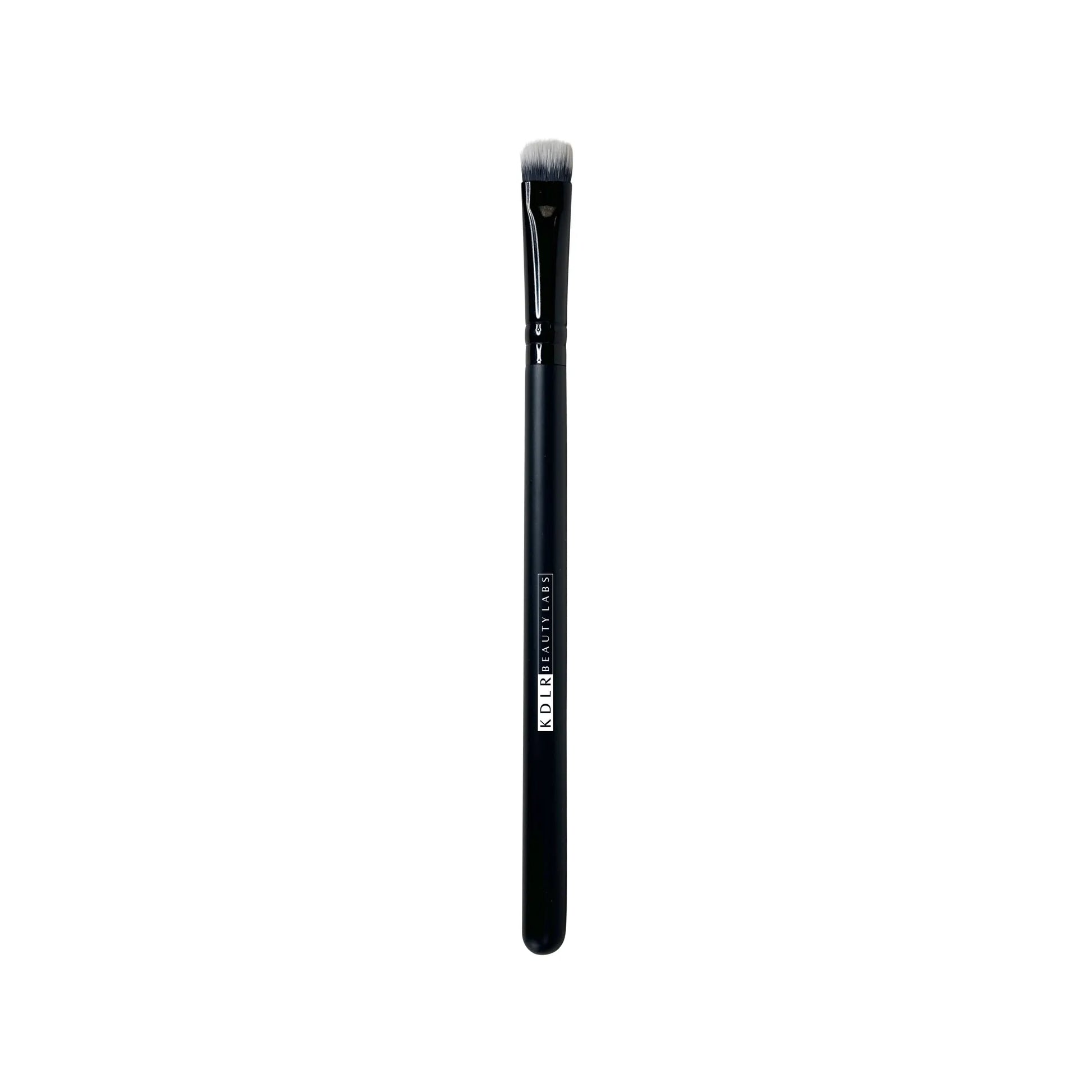 KDLR Beauty Labs Flat Pack and Layer brush, a flat, firm synthetic eyeshadow packing and lid shading brush with black and white bristles and a glossy black handle on a white background.