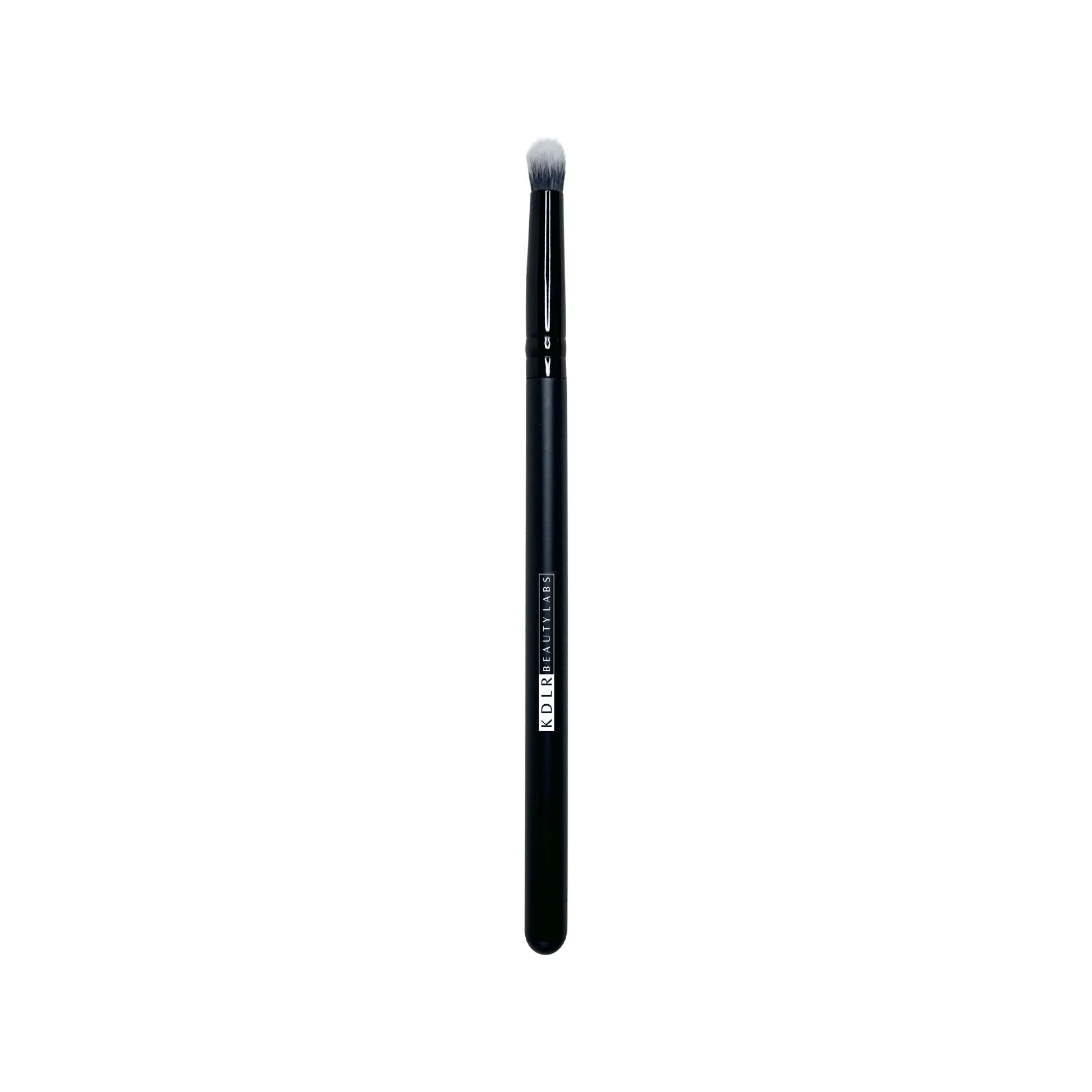 KDLR Beauty Labs Precision Crease and Smudge brush, a small tapered synthetic eyeshadow blending and eyeliner smudging brush with black and white bristles and a glossy black handle on a white background.